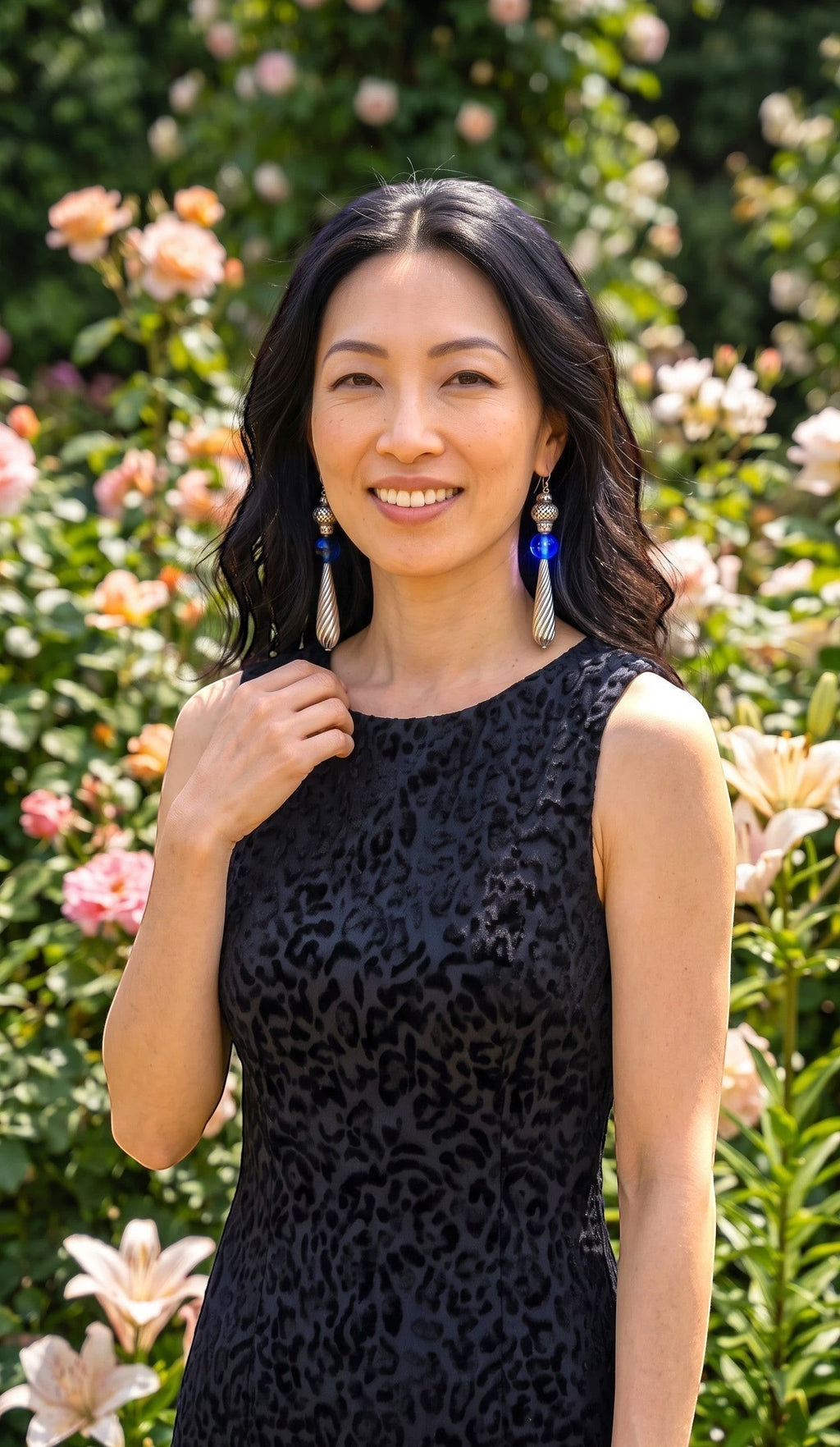 Heartfelt Creations artisan drop earrings with cobalt blue glass spheres and silver teardrop pendants worn by a woman