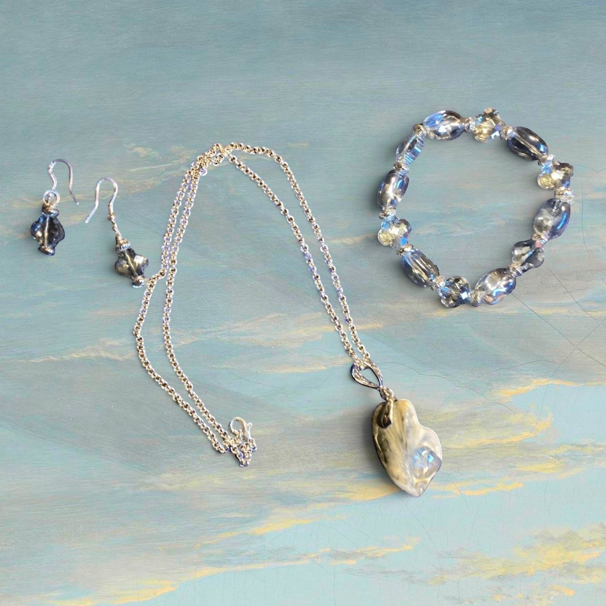 Heartfelt Creations silver-tone jewelry set with blue-grey crystal beads, iridescent pendant necklace, drop earrings, and bracelet.