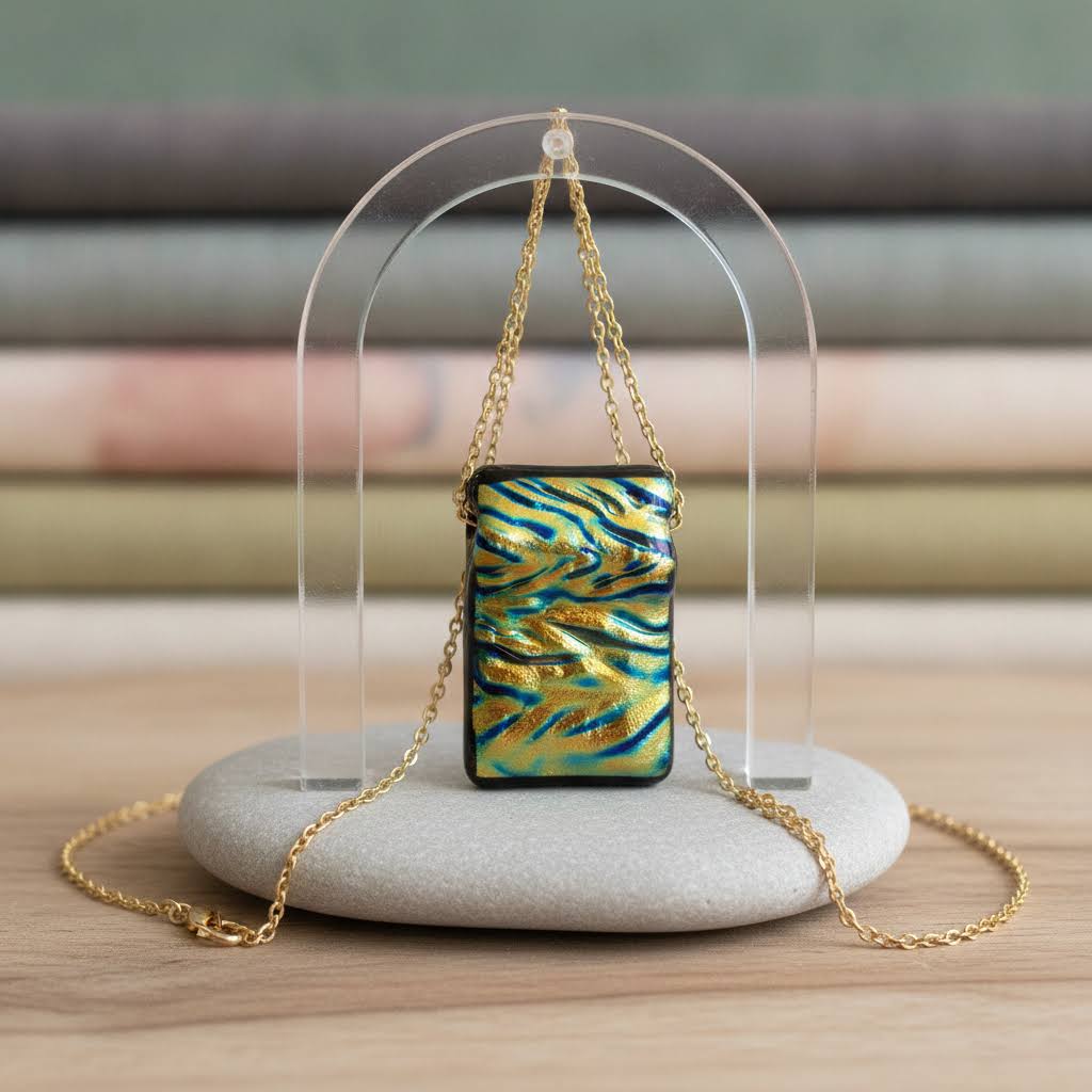 rectangular, iridescent dichroic glass pendant with a wavy, textured surface in shimmering shades of gold, green, and blue, suspended from a delicate, thin gold-colored chain with a small clasp