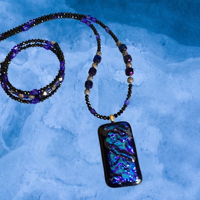 Heartfelt Creations artisan dichroic glass pendant necklace with black, purple, and teal beads on a beaded chain.