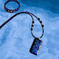 Heartfelt Creations artisan dichroic glass pendant necklace with black, violet, and metallic beaded chain.