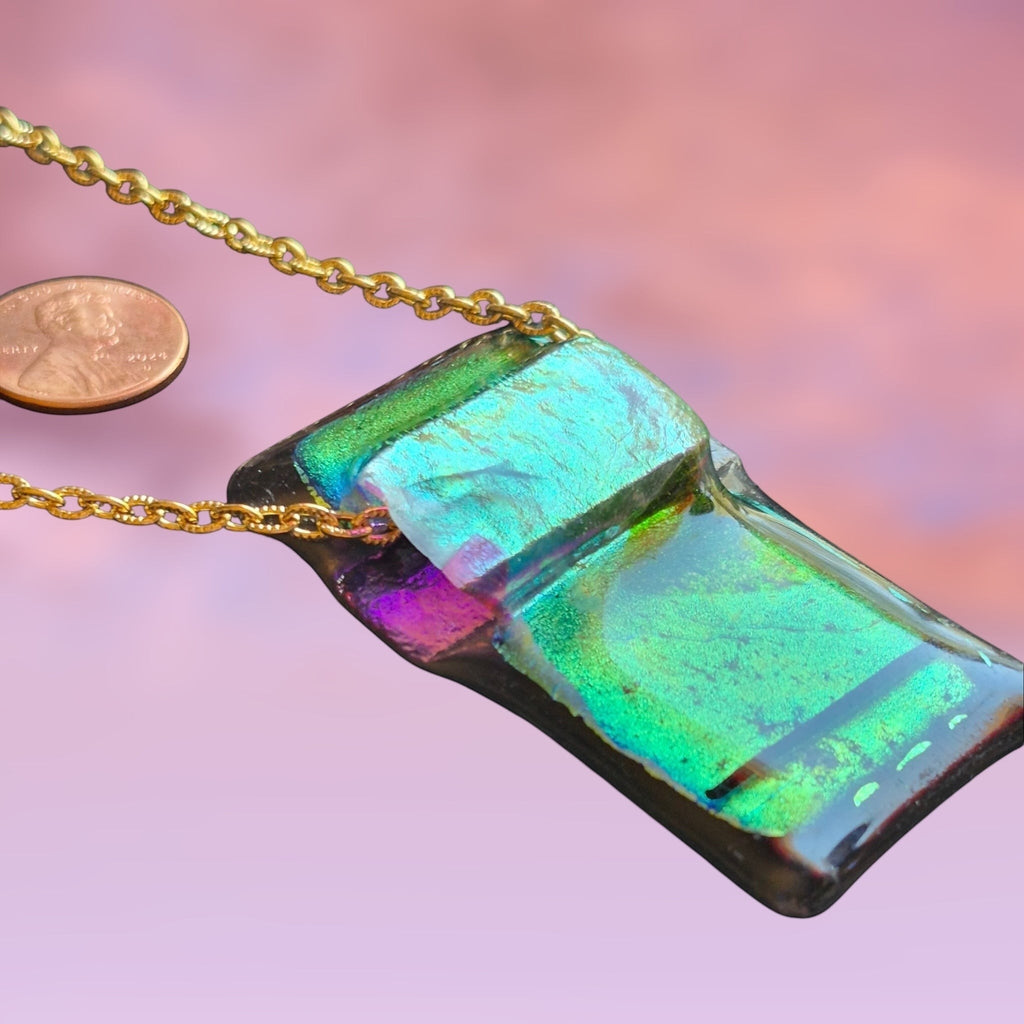 Heartfelt Creations handcrafted dichroic glass pendant in green and black on a gold-tone chain with a penny for scale.