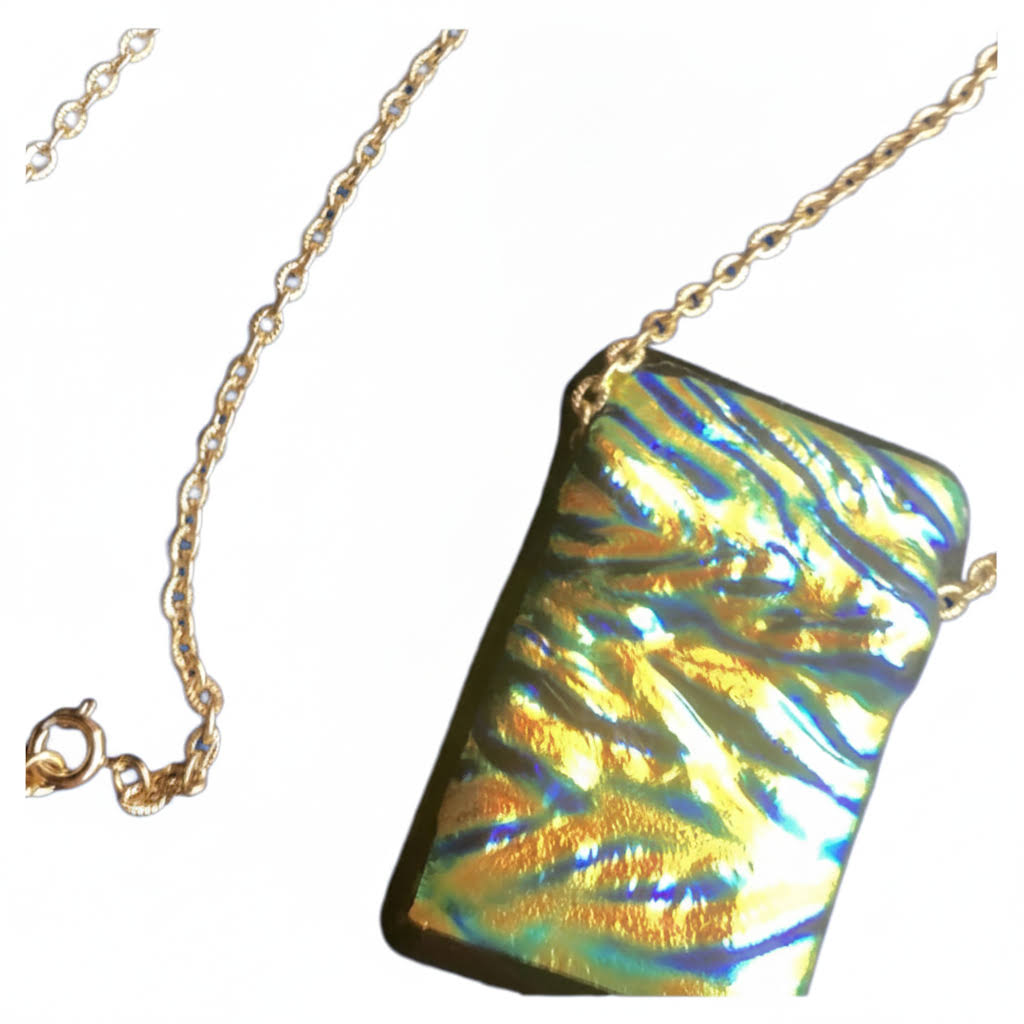 rectangular, iridescent dichroic glass pendant with a wavy, textured surface in shimmering shades of gold, green, and blue, suspended from a delicate, thin gold-colored chain with a small clasp