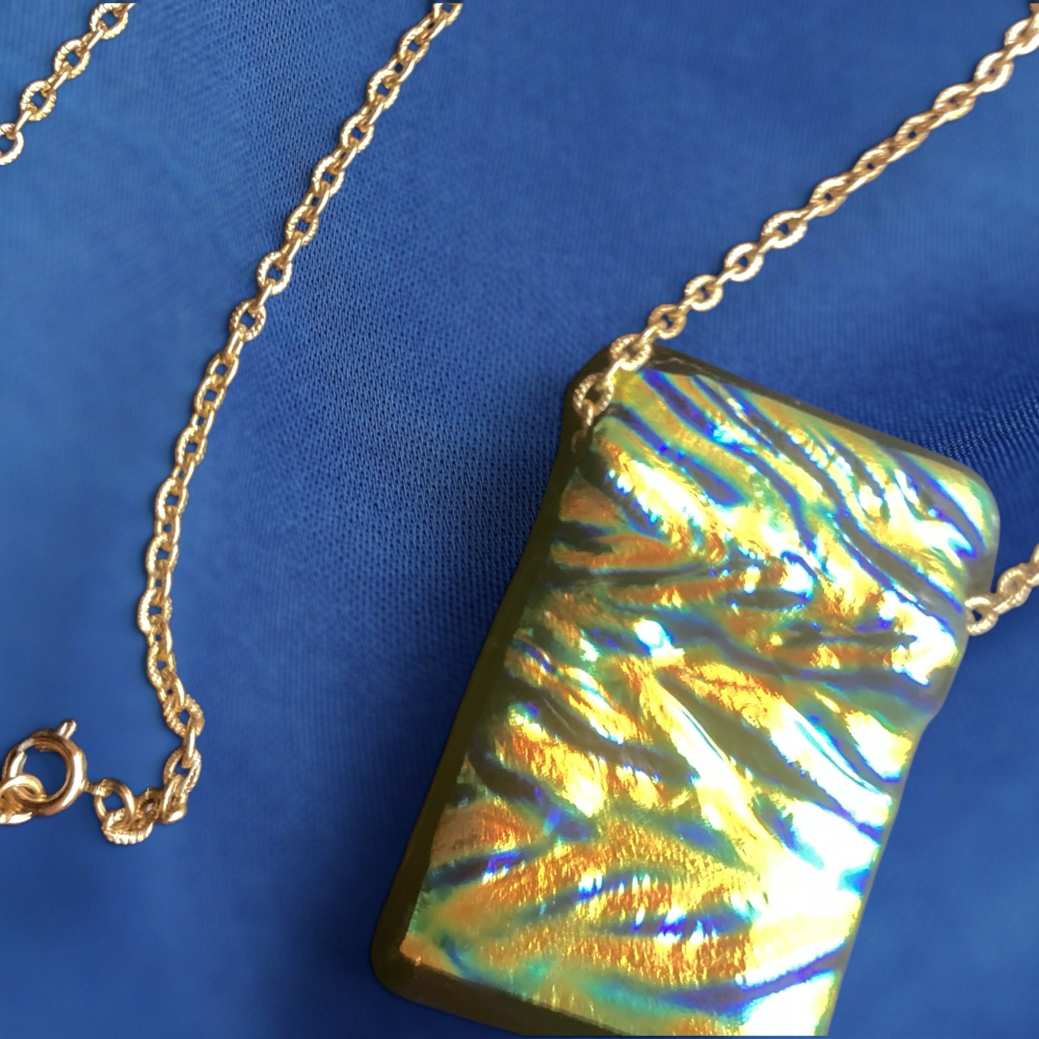 Heartfelt Creations rectangular dichroic glass pendant necklace with iridescent gold and blue hues on a gold-tone chain.
