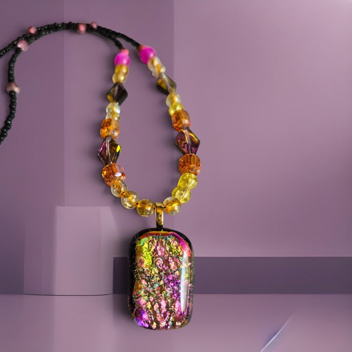 Heartfelt Creations artisan dichroic glass pendant necklace with faceted amber, yellow, and black beads on black cord.