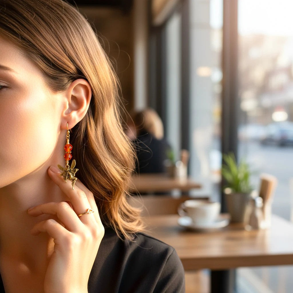 Charms: Detailed, gold-tone whimsical fairy pendants.

Accents: Stacked, vibrant orange faceted glass beads.

Hardware: Gold-tone wire wrapping with fish hook closures.

Style: Lightweight, drop design offering an ethereal and magical look.