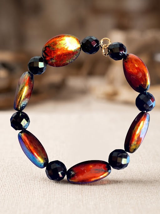 Heartfelt Creations artisan bracelet featuring fiery orange, red, and gold oval beads with black faceted accents.