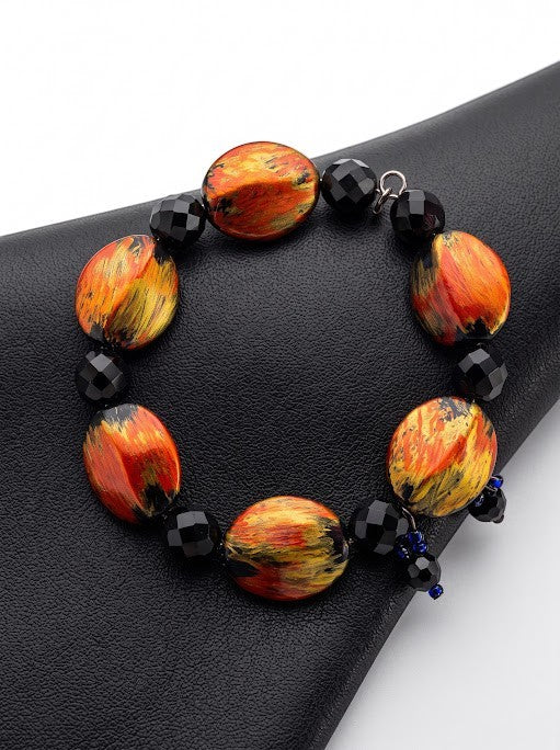Heartfelt Creations artisan bracelet with fiery orange, red, and gold oval beads contrasted by black faceted beads.