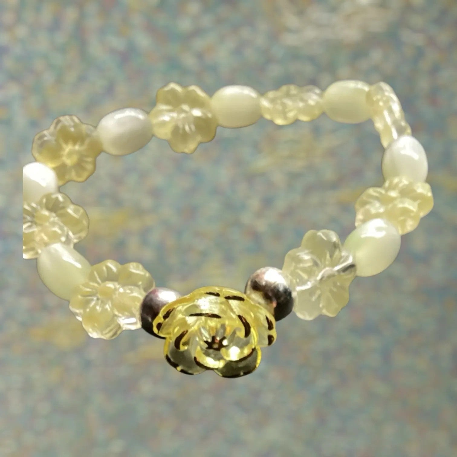 Heartfelt Creations stretch bracelet with creamy white oval beads, translucent yellow floral charms, and a central golden flower charm.