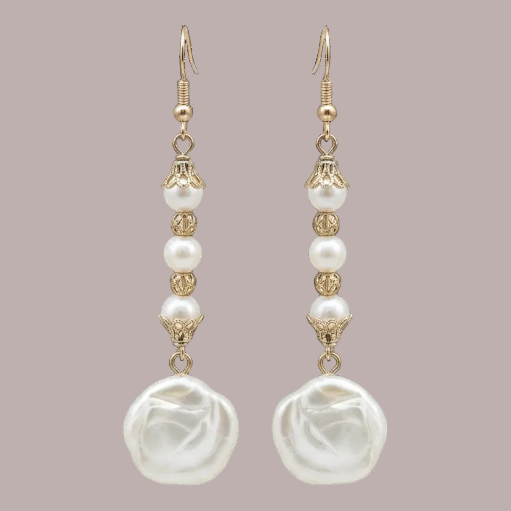 A pair of gold and white drop earrings featuring baroque pearls, faceted beads, and ornate gold metalwork, displayed against a solid muted mauve background.