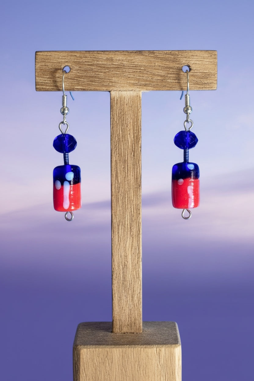 Heartfelt Creations artisan glass bead dangle earrings in royal blue and red with silver hooks on a wooden display