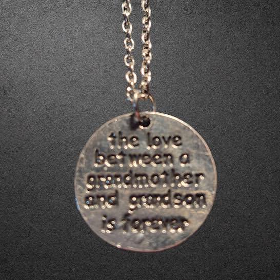 A silver-stainless steel round pendant necklace with engraved text reading 'the love between a grandmother and grandson is forever.'