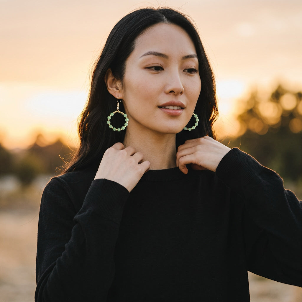 Heartfelt Creations handcrafted hoop earrings with soft green gemstone beads and gold accents worn by a woman