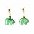 A pair of drop earrings featuring polished green stone elephant charms, accented with a small green bead, a cream-colored round bead, and a gold-colored post.