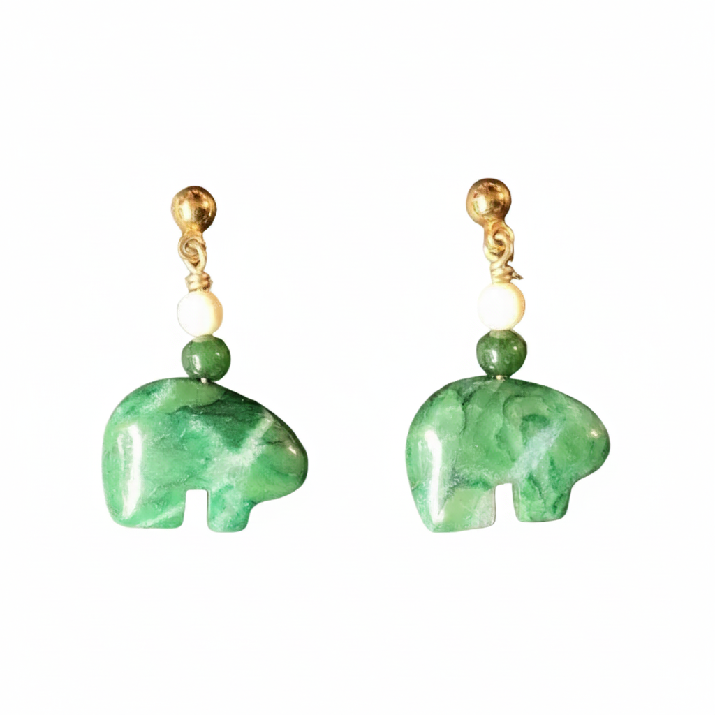 A pair of drop earrings featuring polished green stone elephant charms, accented with a small green bead, a cream-colored round bead, and a gold-colored post.