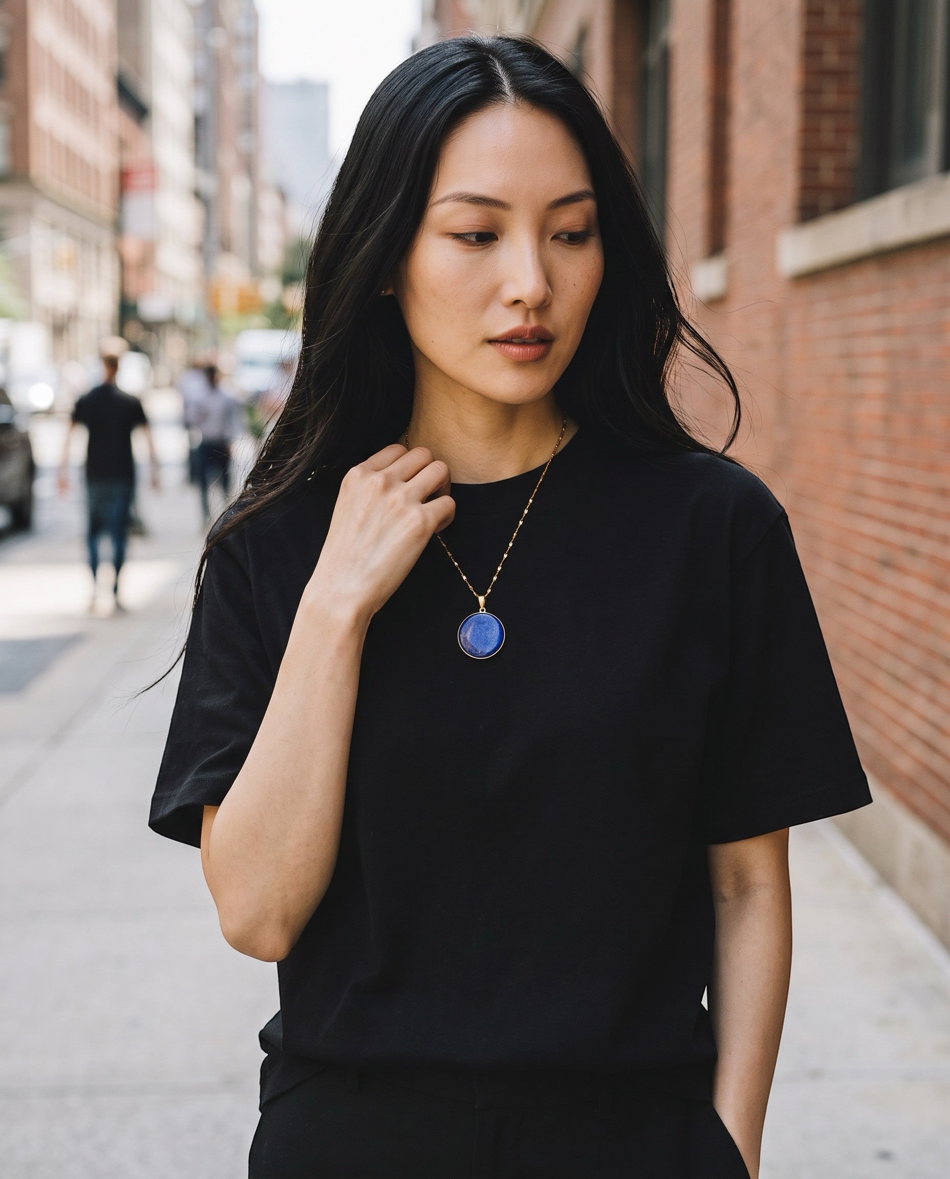 Heartfelt Creations round Lapis Lazuli pendant necklace in gold-tone setting worn by a woman in a black t-shirt