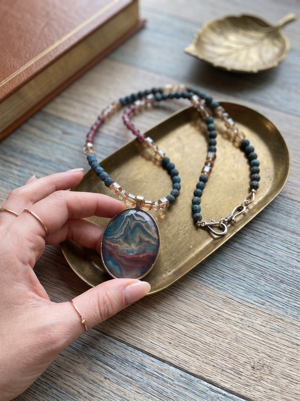 Heartfelt Creations artisan necklace with a marbled oval pendant, blue-grey agate, burgundy, and amber crystal beads.