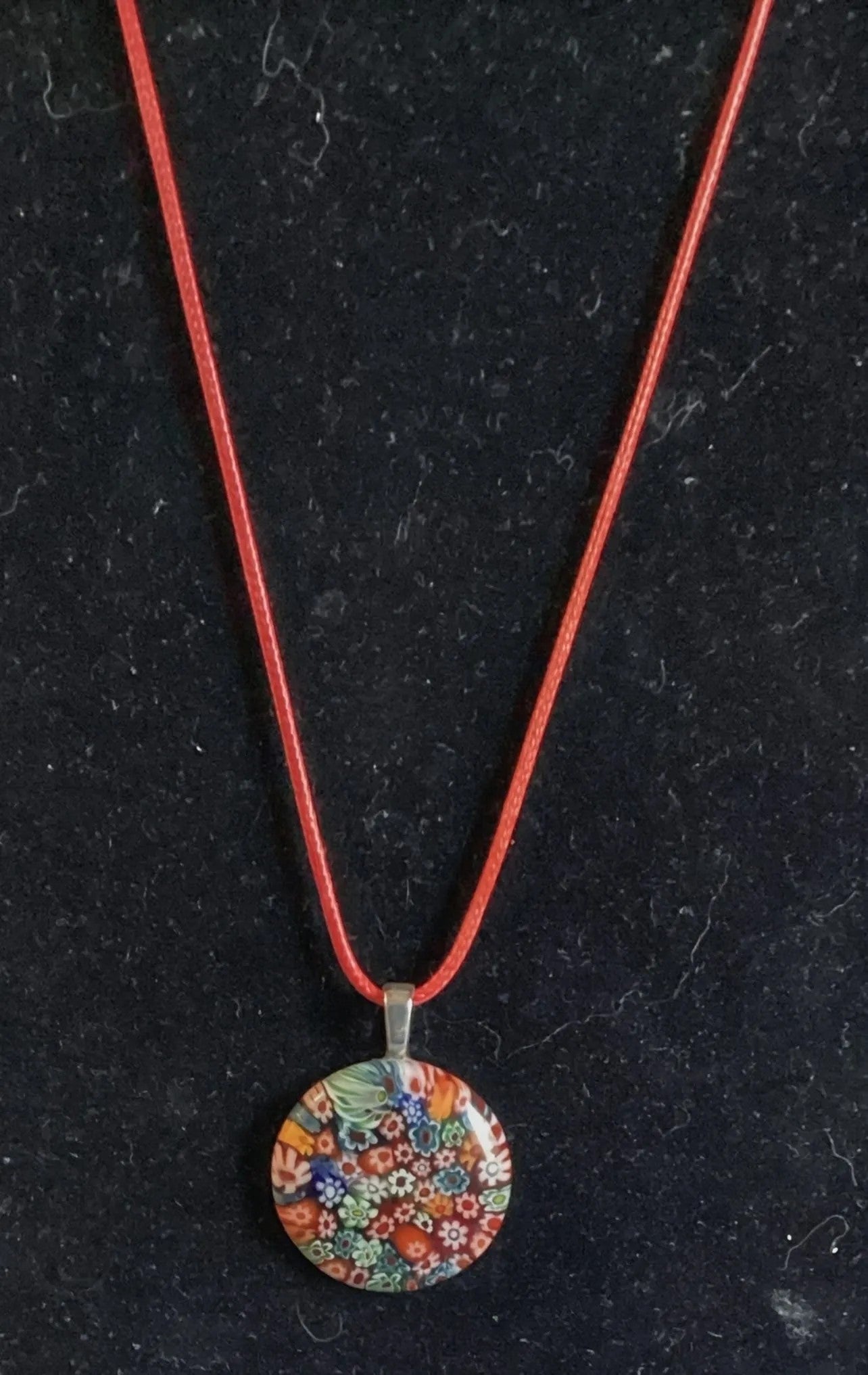 Heartfelt Creations millefiori glass pendant necklace with colorful floral mosaic on a red cord.