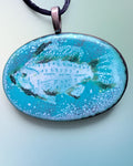 Heartfelt Creations oval enamel pendant featuring a turquoise and teal fish motif on a black cord necklace.