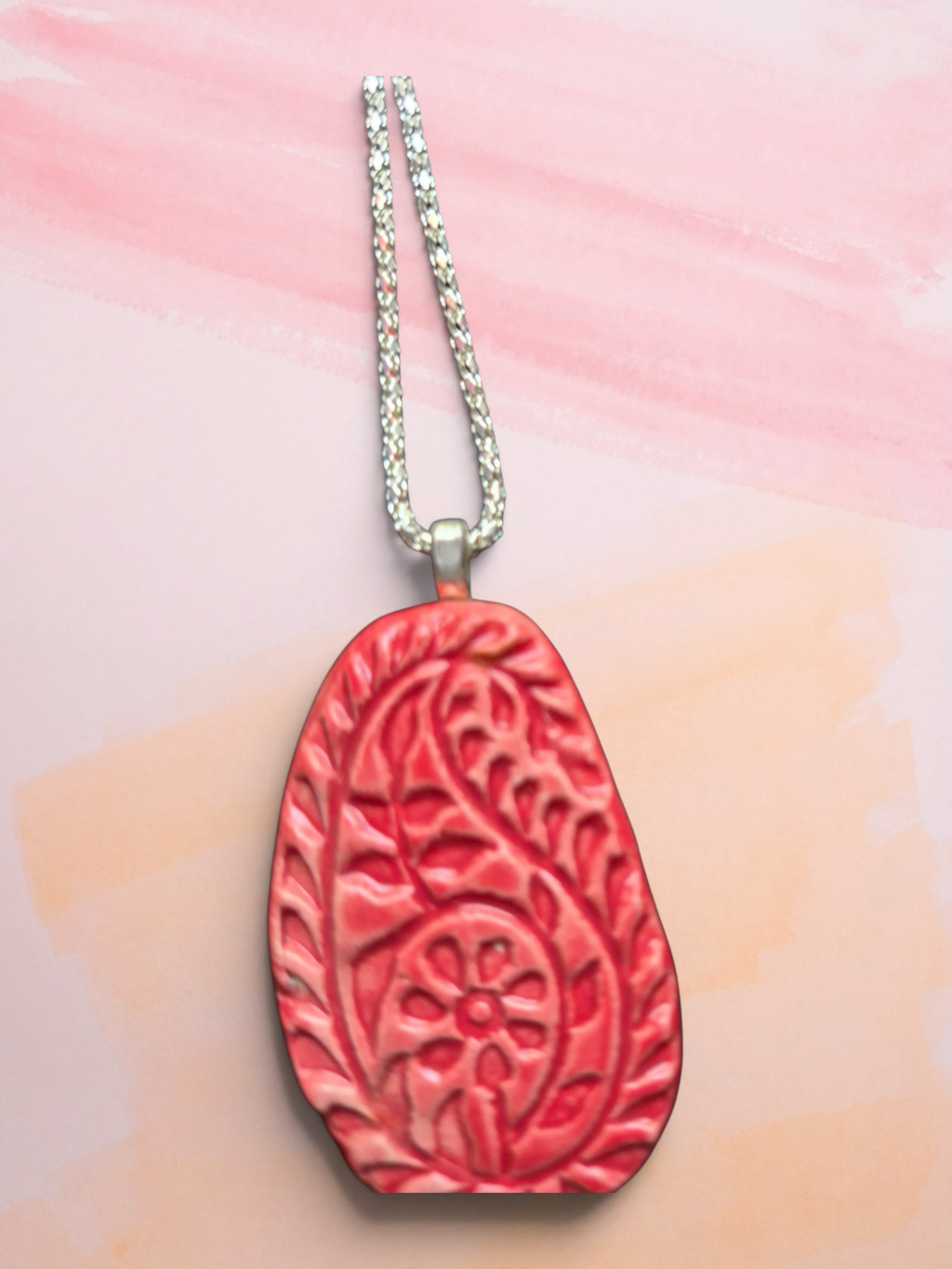 Heartfelt Creations handcrafted coral-red teardrop pendant necklace with embossed paisley motifs on a silver chain.