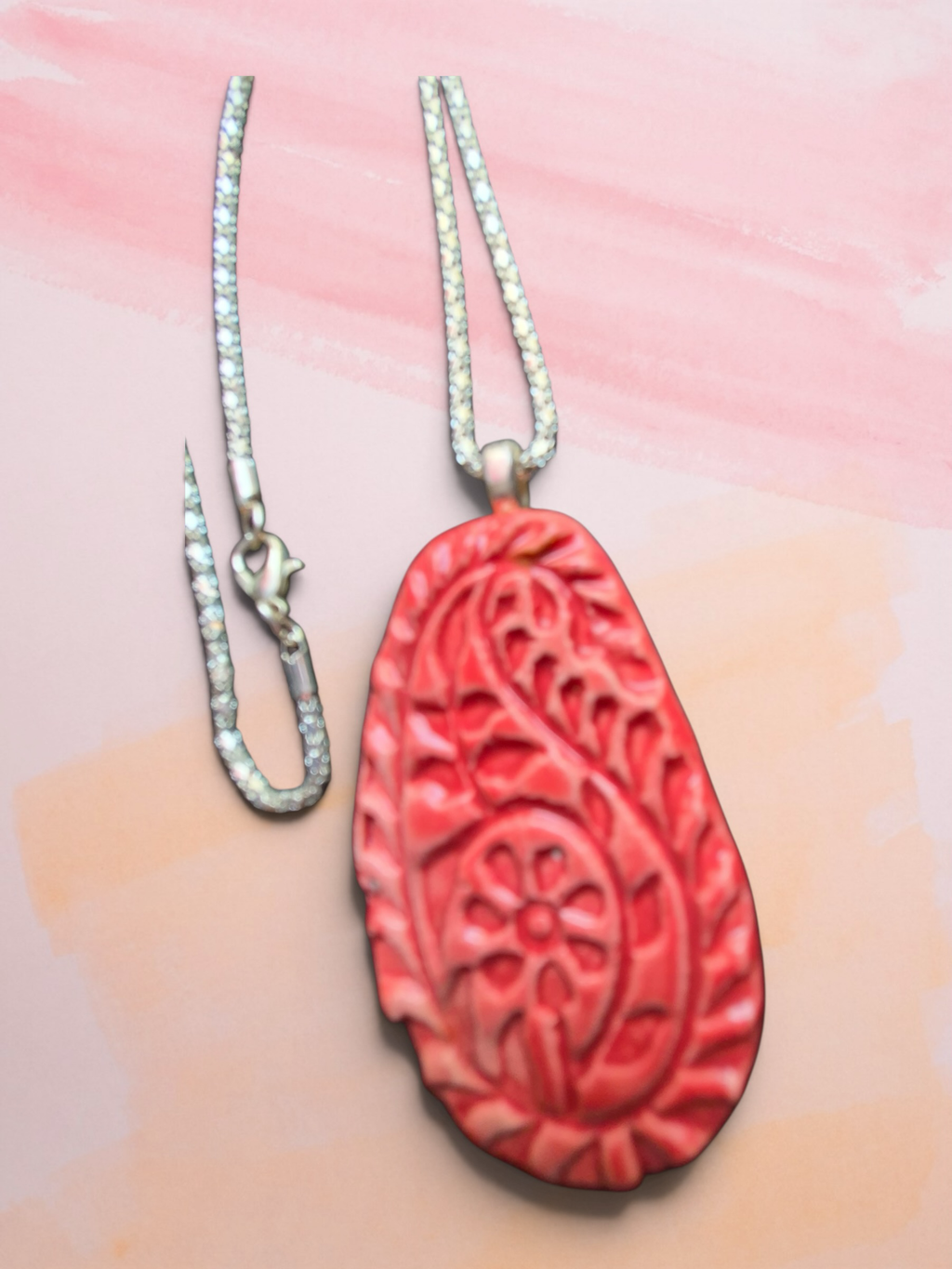 Heartfelt Creations handcrafted coral-red teardrop pendant necklace with embossed paisley motifs on a silver chain.