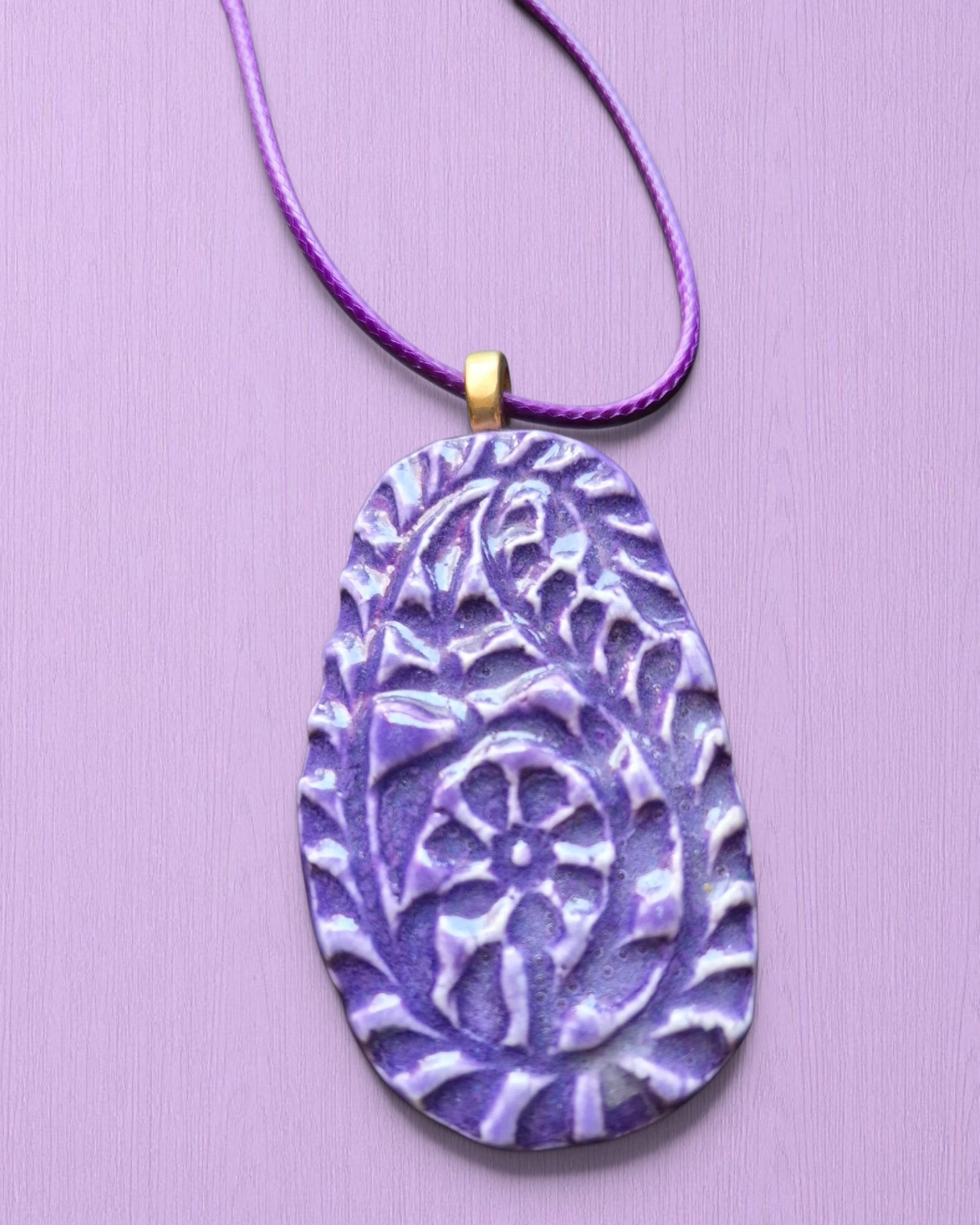 Heartfelt Creations handcrafted purple ceramic pendant necklace with intricate floral texture and glossy glazed finish.