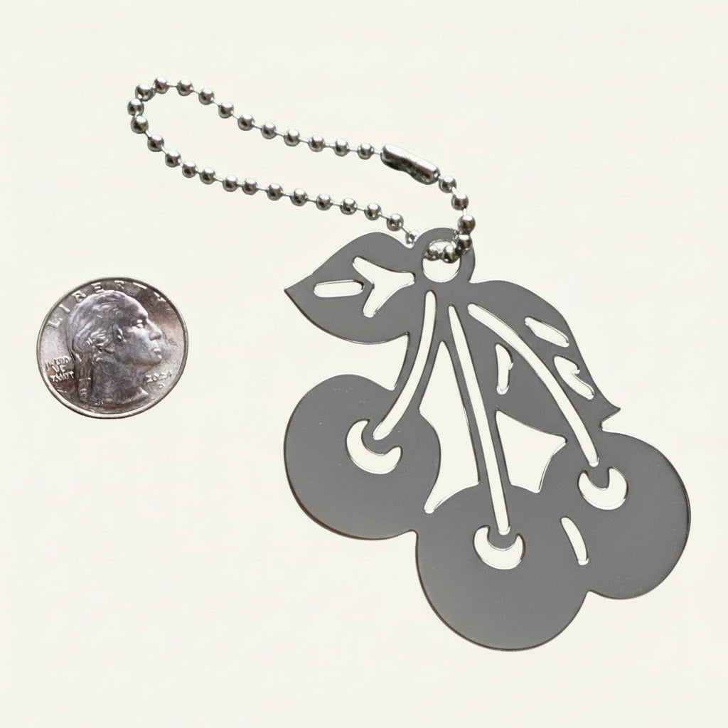 Heartfelt Creations silver-plated brass base metal cherry keychain with a ball-chain attachment shown next to a US quarter coin.