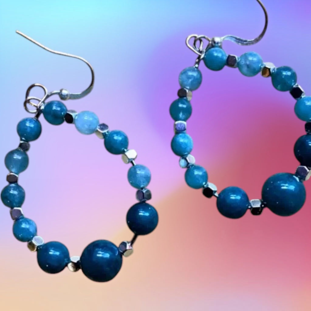 Heartfelt Creations teal and aqua beaded hoop earrings with silver spacers on a bamboo surface