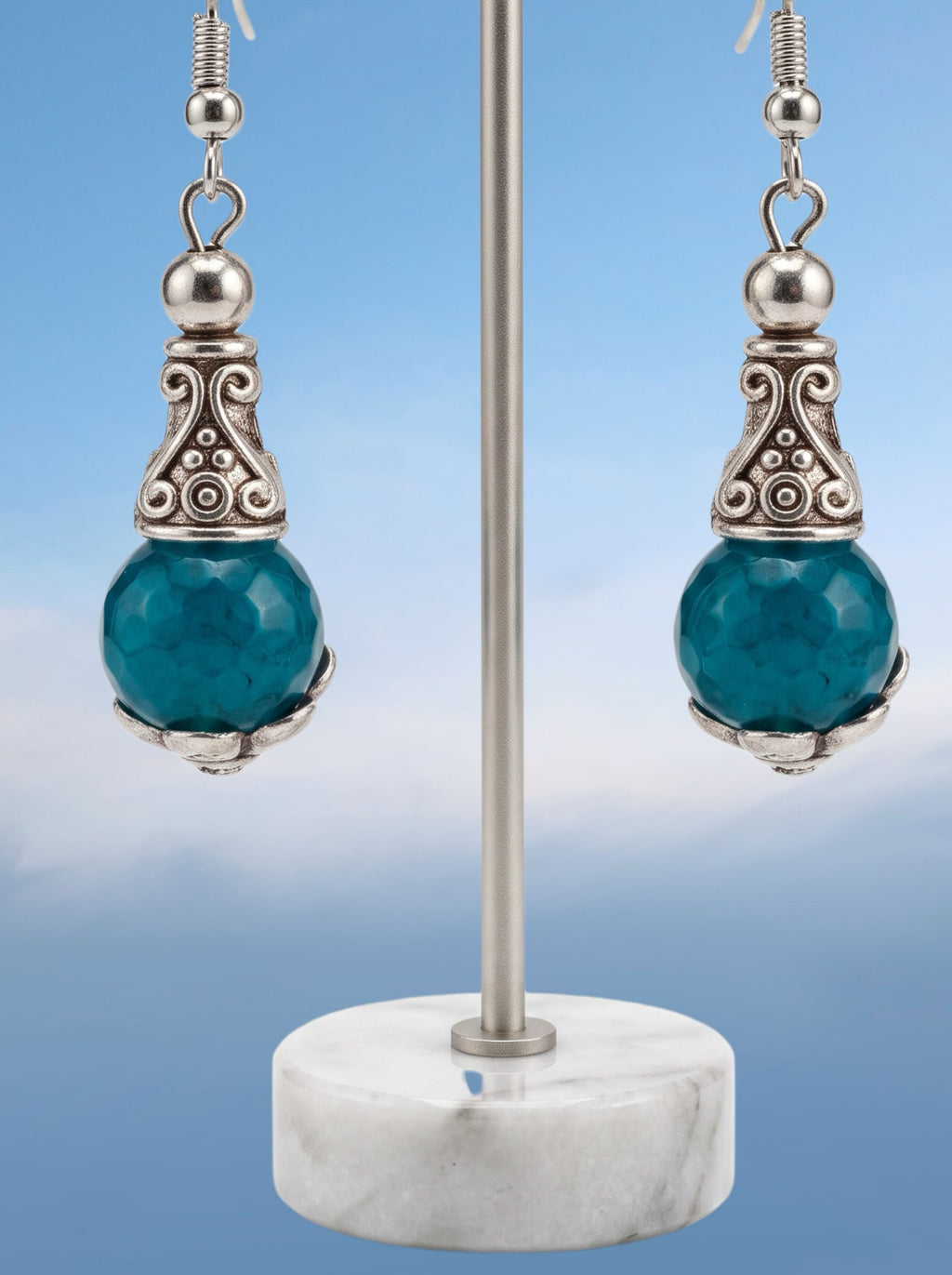 Heartfelt Creations ornate drop earrings featuring faceted teal stones and antiqued silver scrollwork on a display stand.