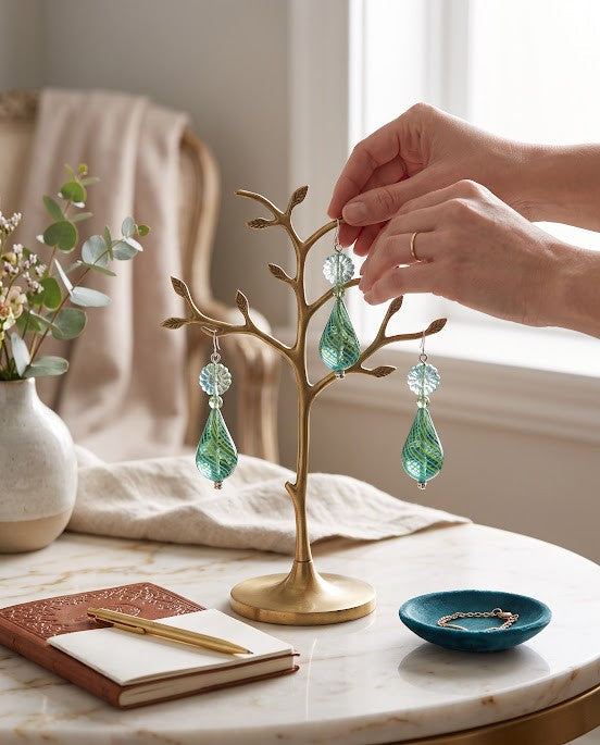 Heartfelt Creations artisan teardrop glass earrings in teal and lime green hanging on a decorative gold tree stand