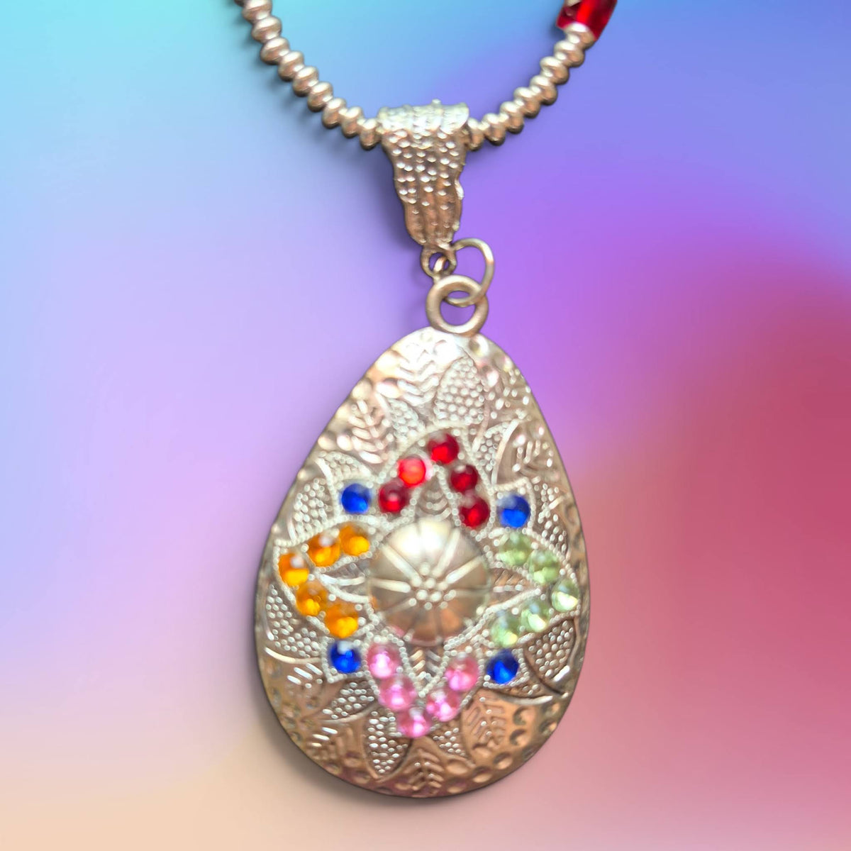 Heartfelt Creations teardrop pendant necklace with embossed floral metalwork and multi-colored crystal embellishments.