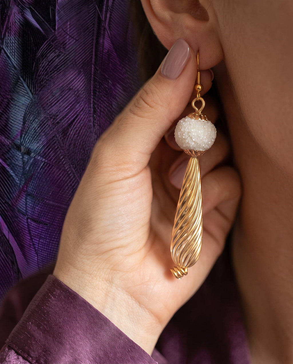 Heartfelt Creations drop earrings featuring a frosted white bead and a textured gold-tone swirl pendant on a model.
