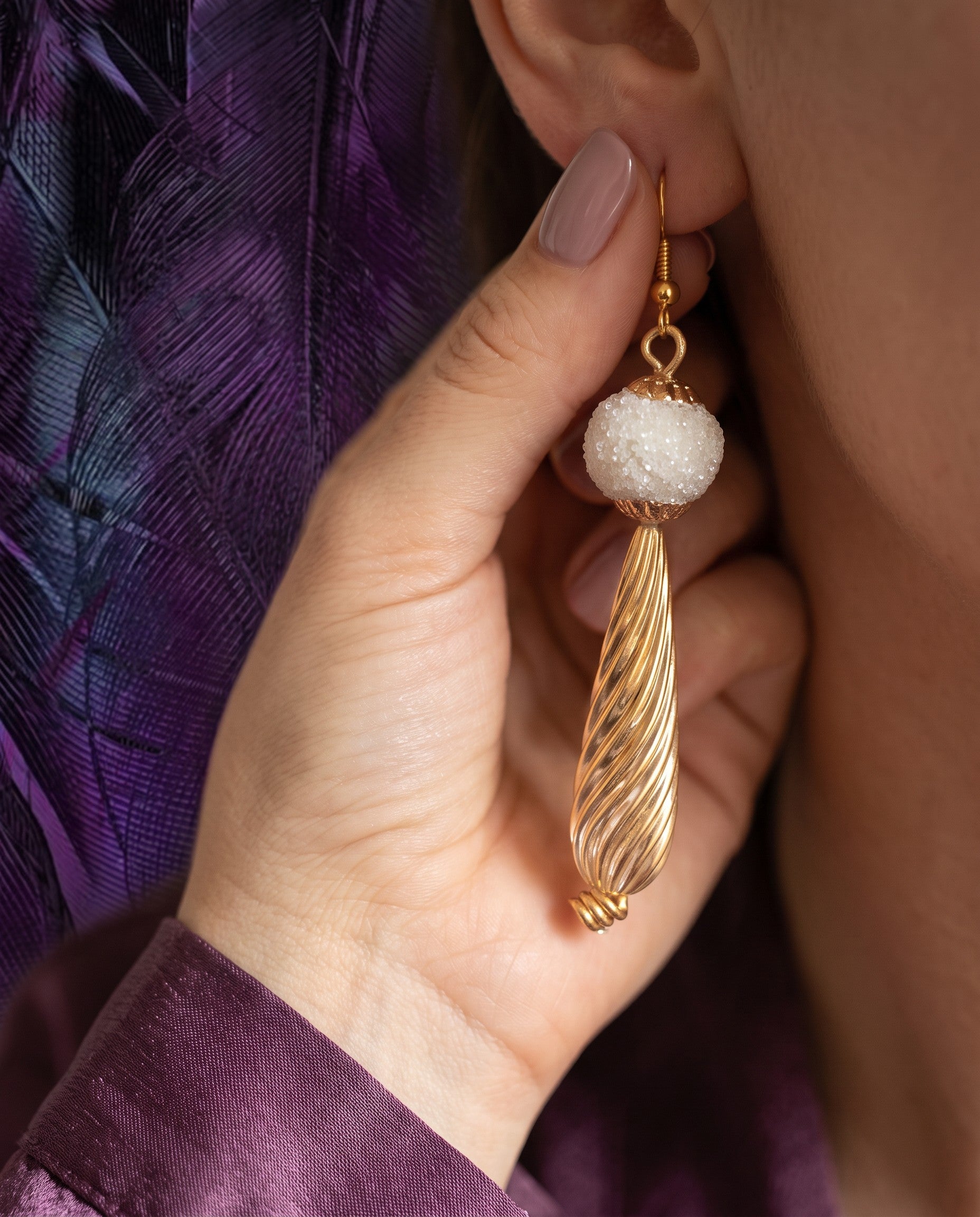 Heartfelt Creations drop earrings featuring a frosted white bead and a textured gold-tone swirl pendant on a model.
