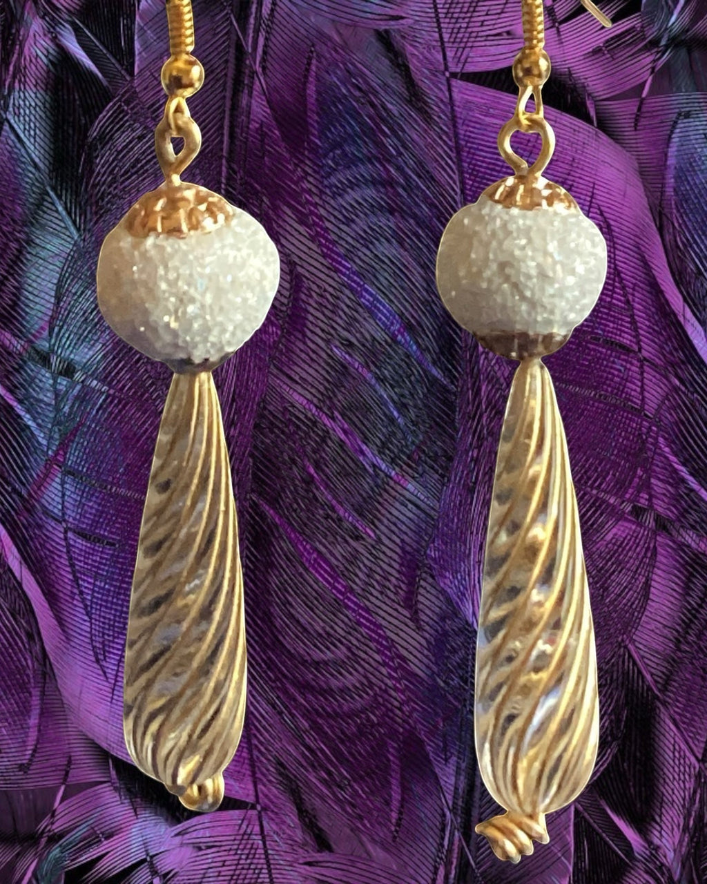 Heartfelt Creations elegant drop earrings featuring frosted white beads and ribbed gold-tone metal on purple feathers.