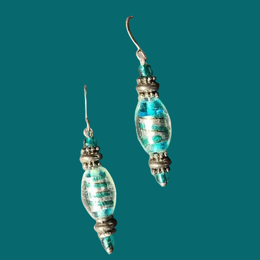 A pair of handmade dangle earrings featuring textured, hammered turquoise and green glass beads with silver-toned metal spacers and fishhook wires, shown against a plain white background.