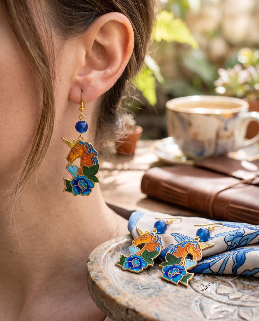 Heartfelt Creations unicorn dangle earrings with blue, orange, and green enamel floral details and gold-tone finish.