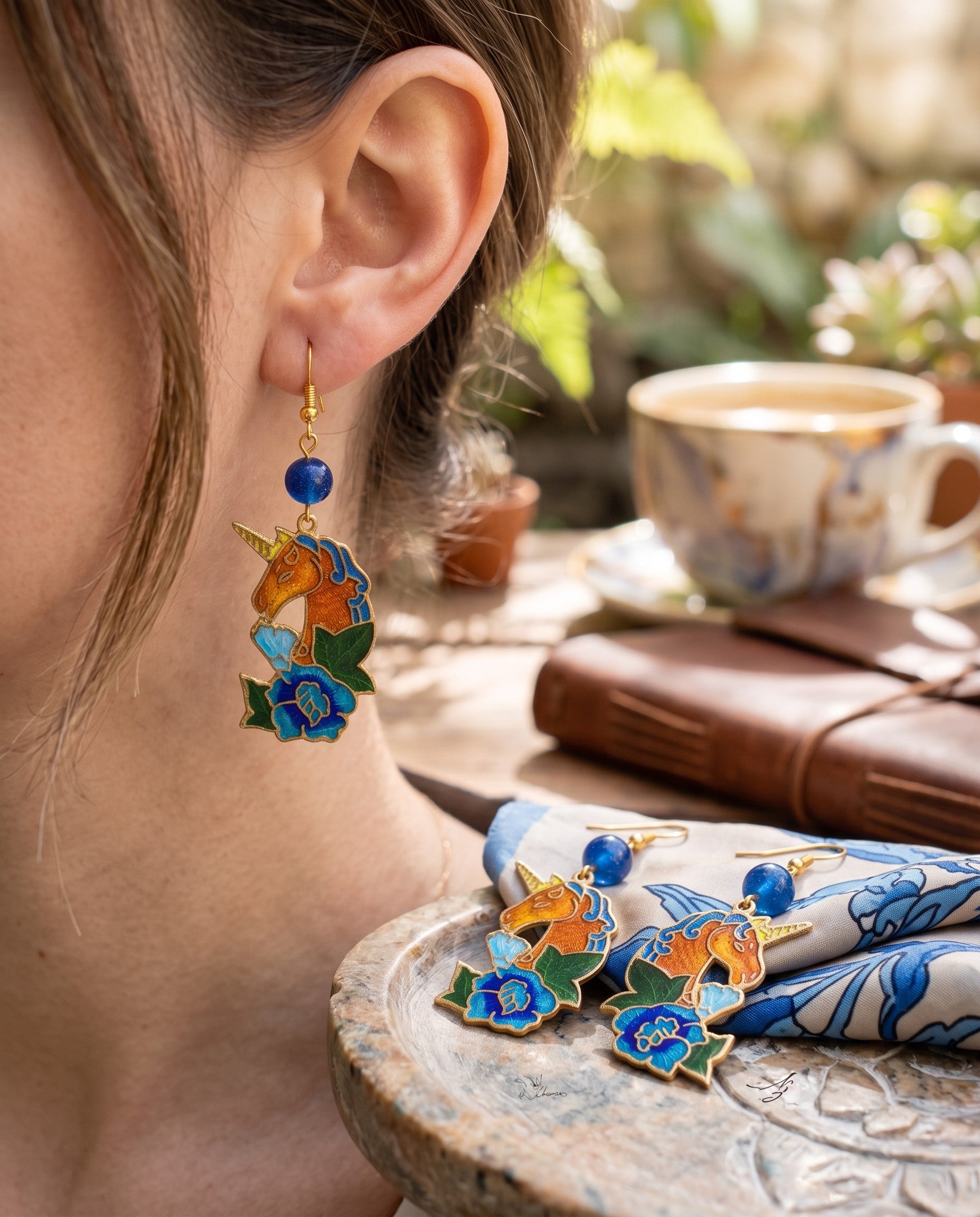 Heartfelt Creations unicorn dangle earrings with blue, orange, and green enamel floral details and gold-tone finish.