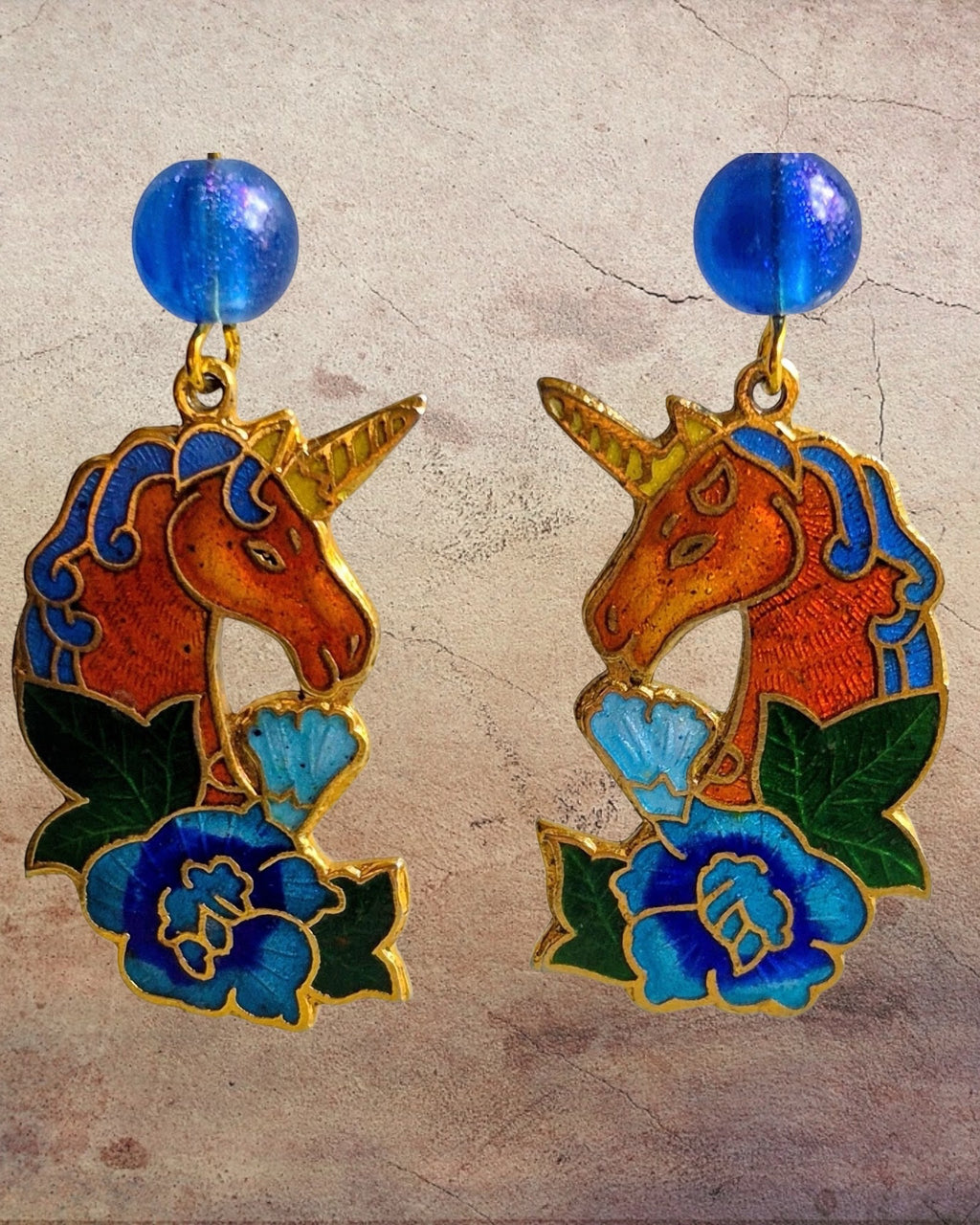 Heartfelt Creations unicorn dangle earrings with vibrant enamel, floral accents, and blue beads in a gold-tone finish.