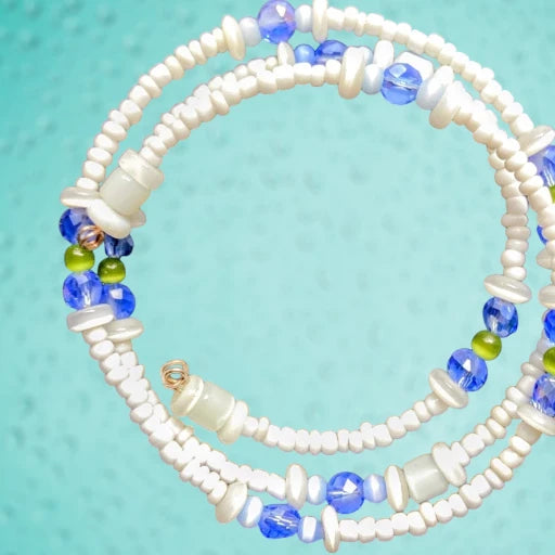Heartfelt Creations' handmade jewelry set featuring a necklace and a multi-strand bracelet, both crafted with a mix of small, round, white, blue, and green beads, with the necklace featuring a prominent, rectangular, fused glass pendant with a vibrant blue, green, and white abstract design.