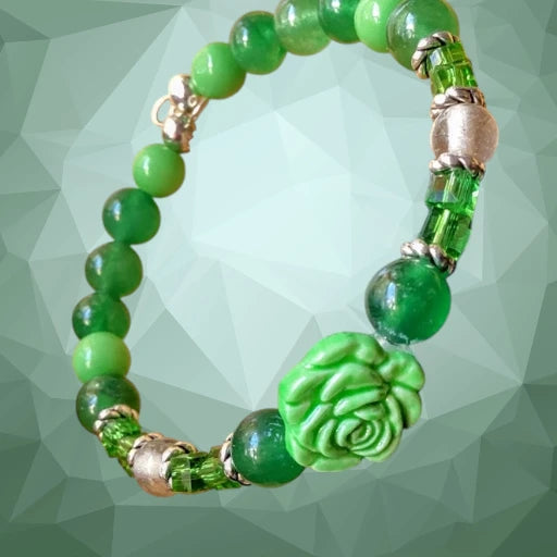 Heartfelt Creations' offers this stunning, nature-inspired beaded necklace and bracelet set. Featuring a vibrant palette of lush greens, this set is designed to add a touch of botanical elegance to any outfit. The centerpiece of the necklace is a beautifully detailed, frosted glass floral charm that captures the essence of a blooming rose, complemented by a variety of green beads that offer a rich, multi-textured look. The matching bracelet echoes this design, creating a cohesive and polished aesthetic.