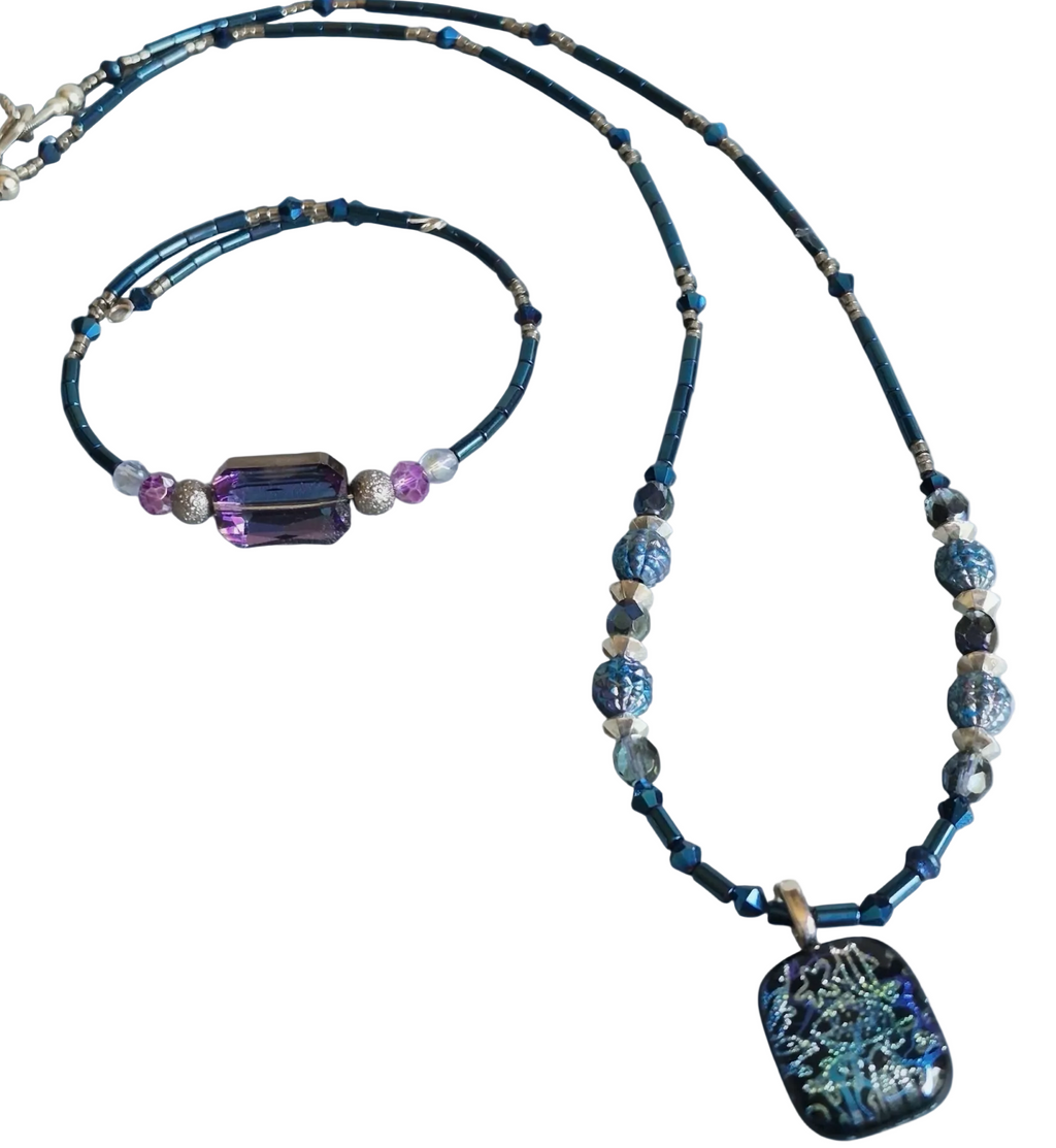 A beaded necklace with a rectangular iridescent shell pendant, displayed alongside a matching beaded bracelet on a plain white background.