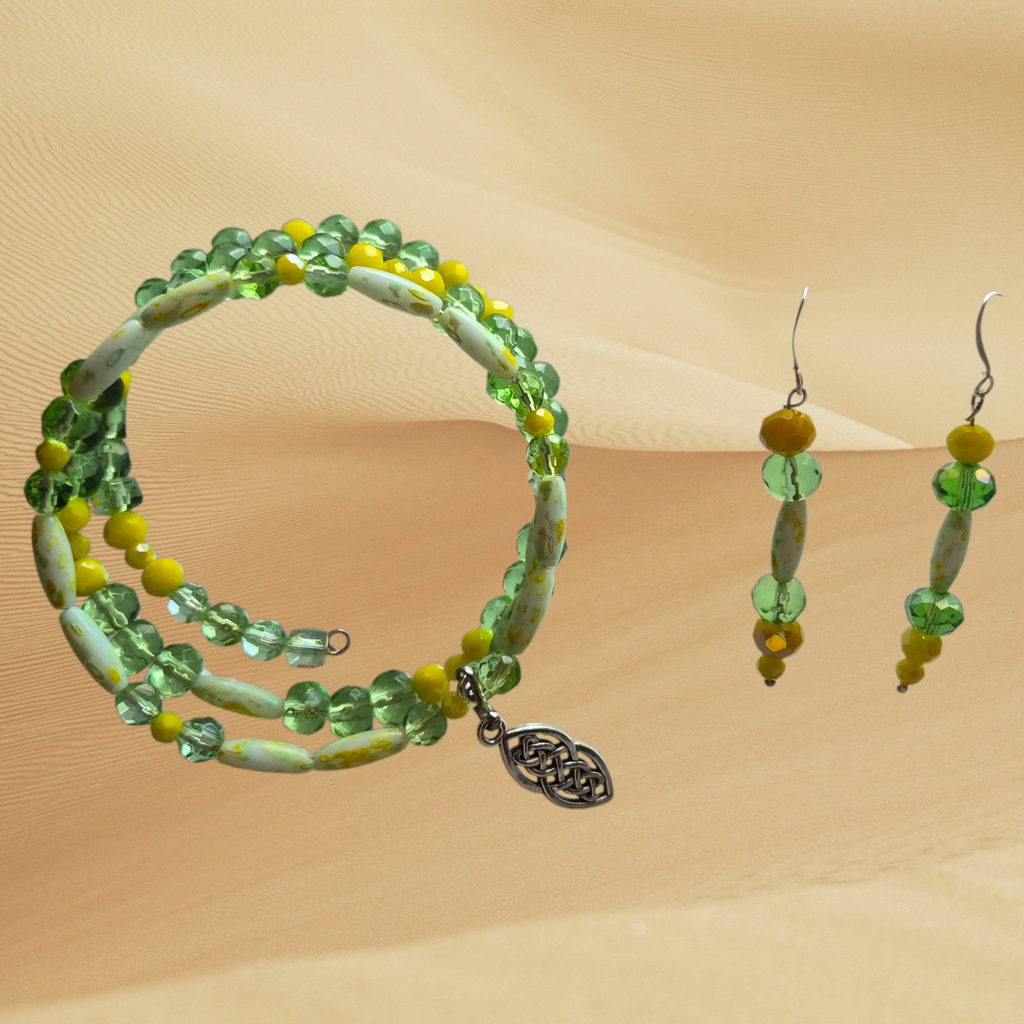 A matching jewelry set featuring a beaded necklace and hoop earrings with green, blue, and white beads on a textured beige background.