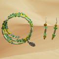 A matching jewelry set featuring a beaded necklace and hoop earrings with green, blue, and white beads on a textured beige background.