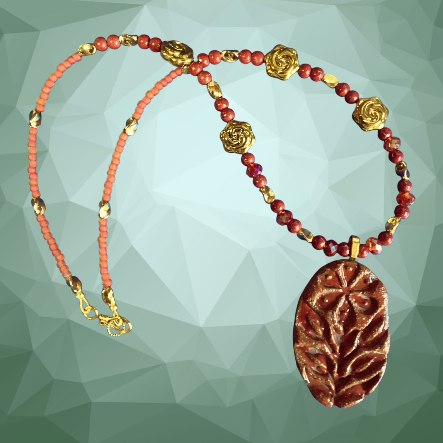 Necklace with red beads and a decorative pendant on a geometric green background