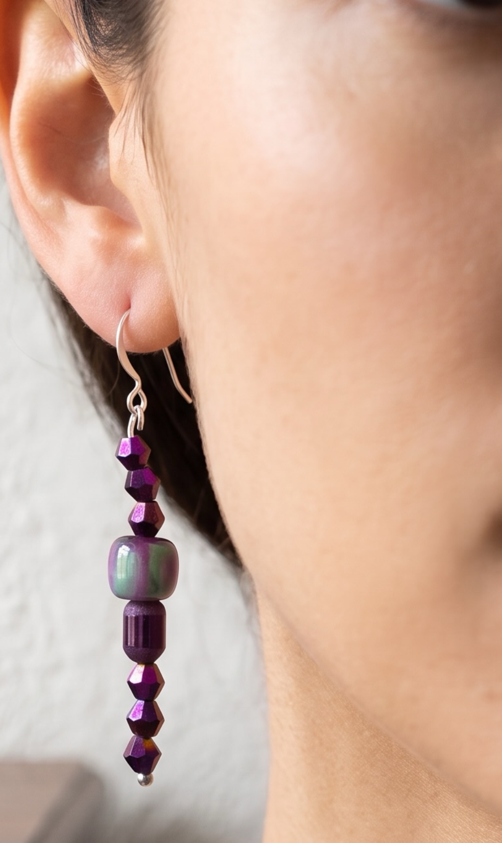 A close-up lifestyle shot of a woman wearing a dangling beaded earring, 