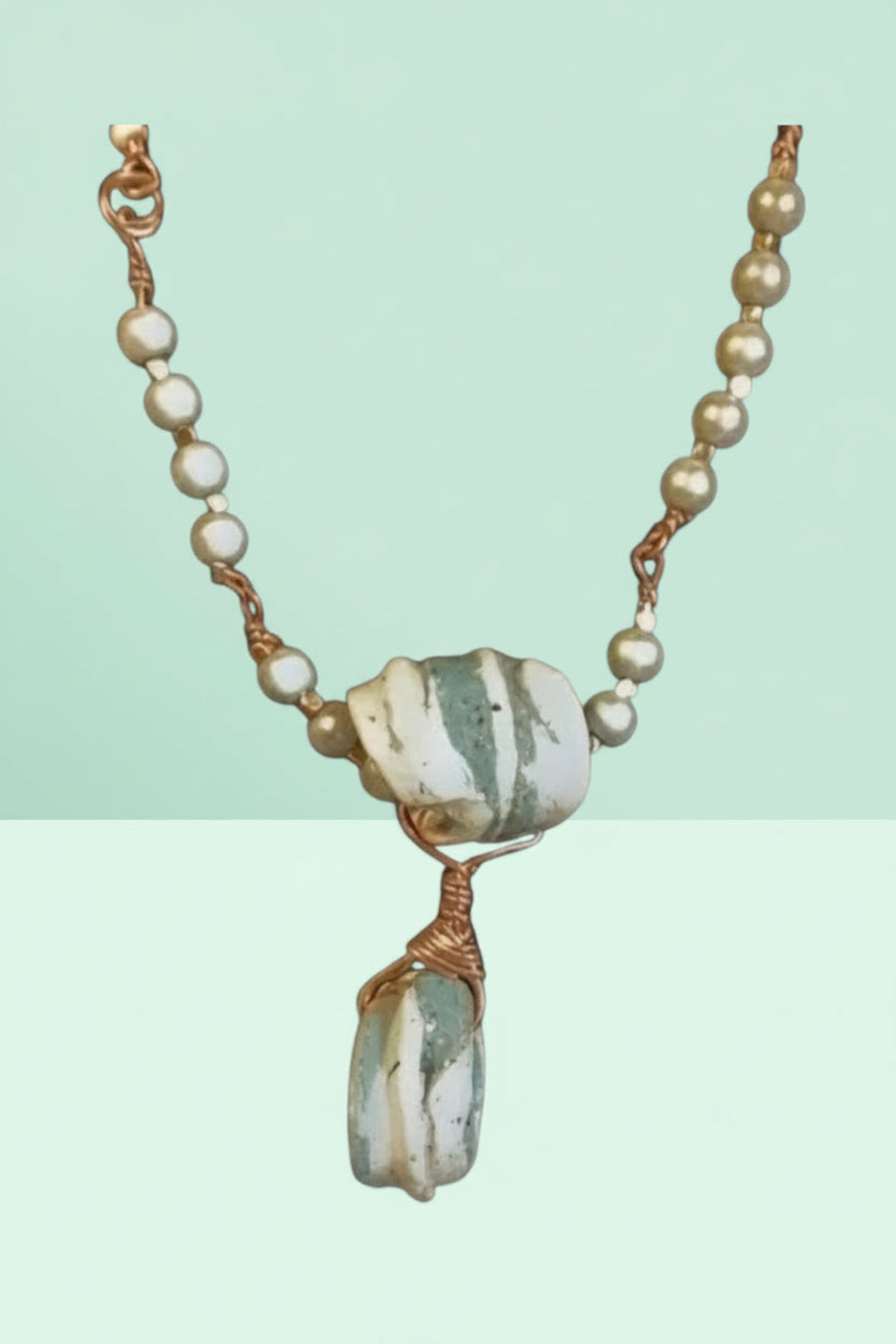 Necklace with stone pendant and pearl beads on a light green background
