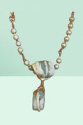 Necklace with stone pendant and pearl beads on a light green background