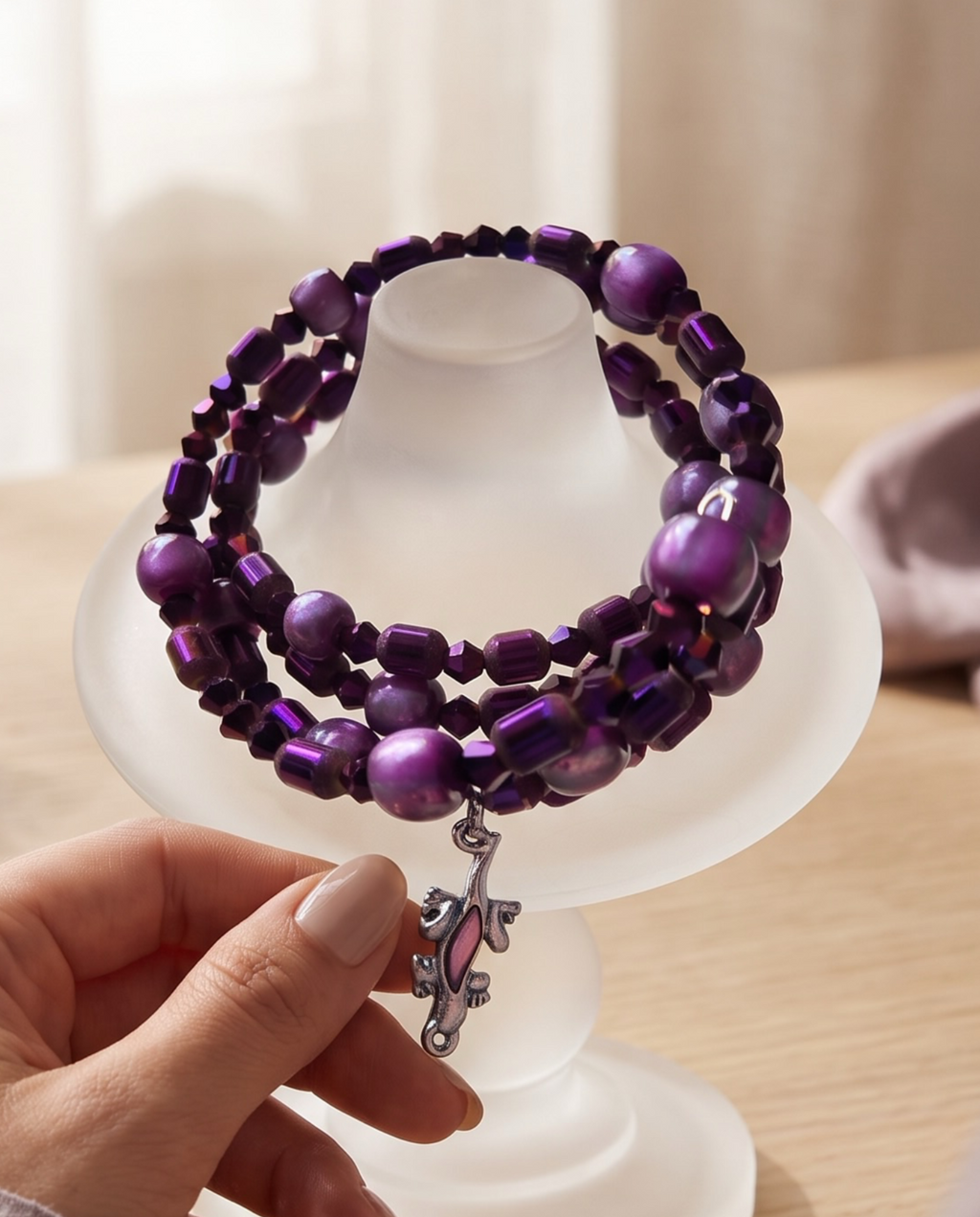 A multi-strand beaded bracelet with white cylindrical beads, blue round beads, gold-toned spacer beads, and a silver-toned bell charm, displayed on a bright blue background.