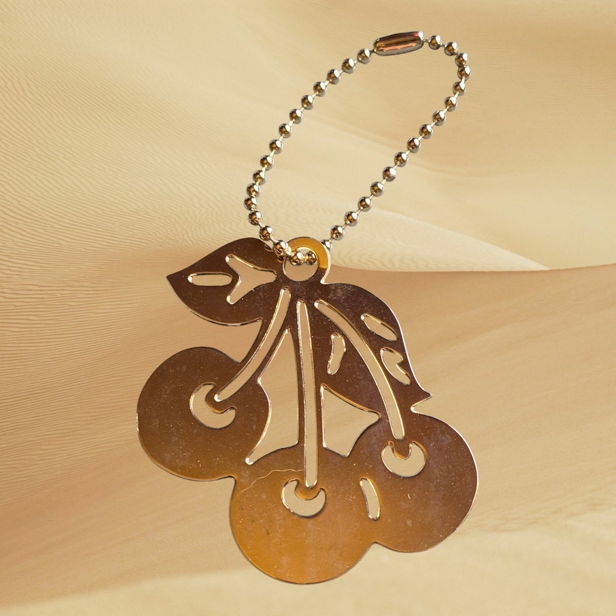 Hand-designed by Heartfelt Creations, you can add a touch of playful elegance to your everyday essentials with your choice of an 18k gold plated Brass cherry keychain or backpack/bag accessory