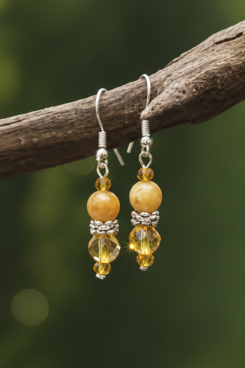 Heartfelt Creations' handcrafted jewelry set featuring a  Bumblebee Jasper and 925 silver plated pendant necklace and matching earrings.  The necklace is composed of small, faceted yellow and orange beads, a large oval-shaped, polished stone pendant with a yellow and white marbled pattern, and a decorative, ornate silver-toned metal clasp, and the earrings consisting of a single yellow bead and a smaller, matching orange bead on a silver-toned hook.